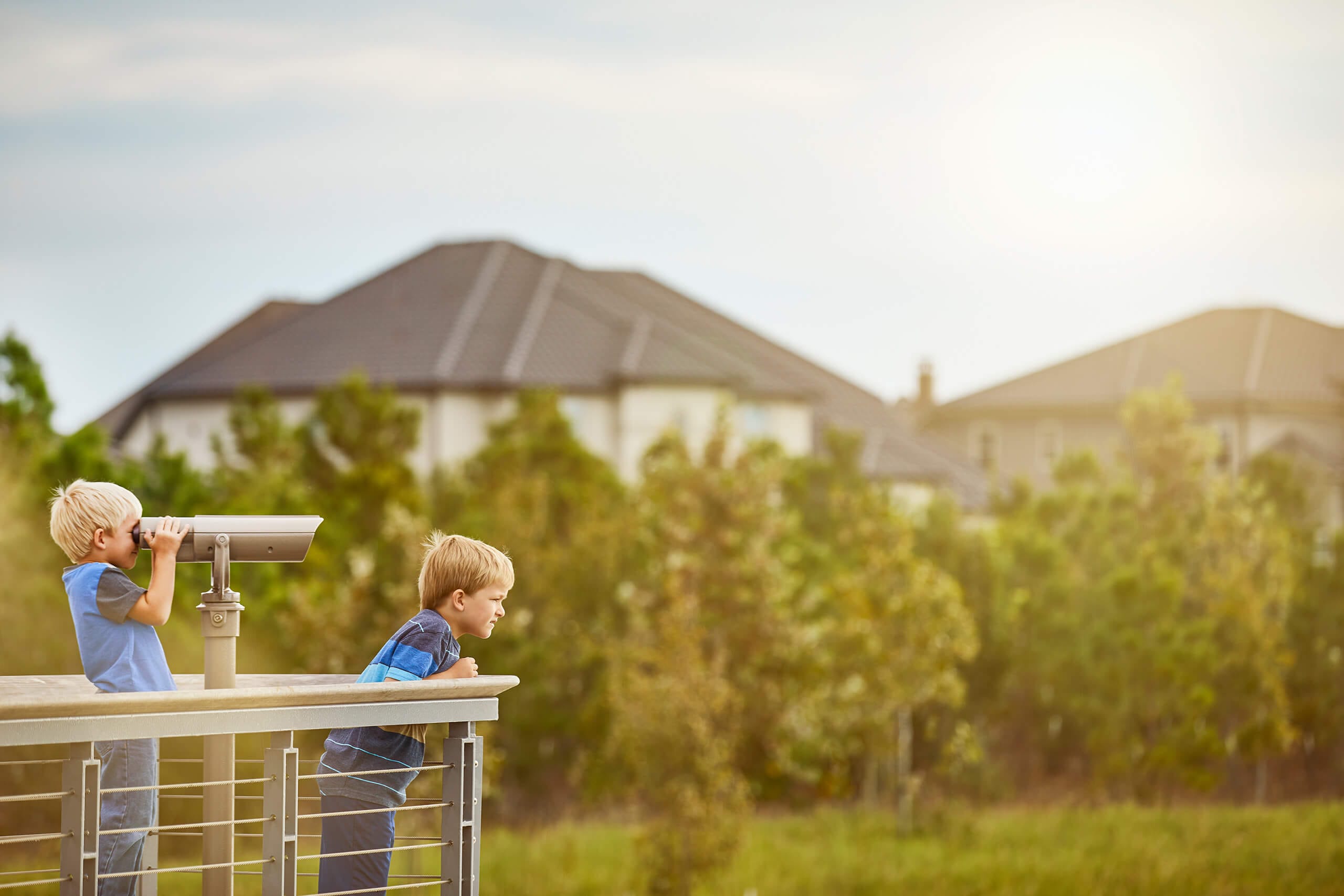 Two young friends enjoy community binoculars to enjoy viewing nature from a scenic overlook in Bridgeland.